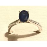 An 18ct white gold sapphire & diamond ring, the claw set oval sapphire weighing over a carat, raised