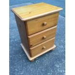 A pine dwarf chest with three knobbed drawers, raised on bun feet. (17.5in x 13.75in x 24.5in)