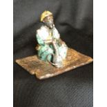 A old painted bronze modelled as an arab with hookah pipe on rug - cast Bergm Mark. (2.25in)