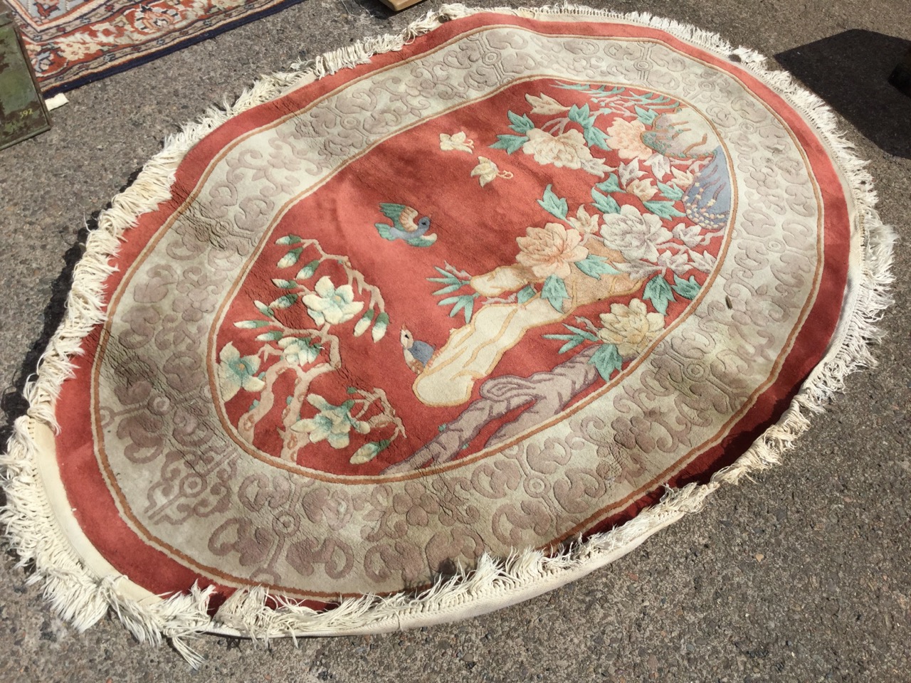 An oval Chinese thick pile wool rug woven with panel of birds, butterflies and foliage on russet