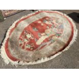 An oval Chinese thick pile wool rug woven with panel of birds, butterflies and foliage on russet