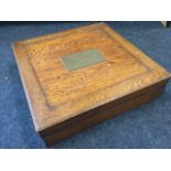 A square Edwardian dovetailed oak box with brass hinges, the panel to lid mounted with plaque