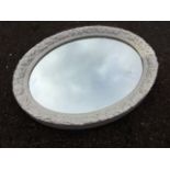 An oval white painted gesso moulded mirror, the glazed plate later. (23.5in x 19.25in)