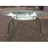 A contemporary oval plate glass dining table, the bevelled top with etched glass undershelf raised