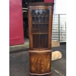 A serpentine fronted mahogany corner cabinet, with moulded dentil cornice above an astragal glazed