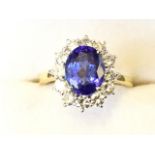 An 18ct yellow gold tanzanite & diamond cluster ring, the oval claw set tanzanite weighing over