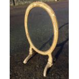 An oval C19th gilt & gesso firescreen, the frame with egg & dart moulding on acanthus leaf supports,