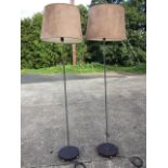 A pair of contemporary standard lamps with suede shades on chrome poles, the circular wood bases