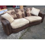 A concave fronted curved leather sofa in two pieces, with fluted padded arms and loose cushions. (