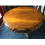 A circular yew drum table, the top inlaid with ebony stringing above a frieze with two drawers,