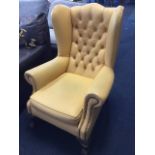 A button upholstered wing armchair with loose cushion to seat, the arms with brass studding,