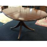 An oval mahogany dining table, the moulded top on bulbous turned column, with quadripartite sabre