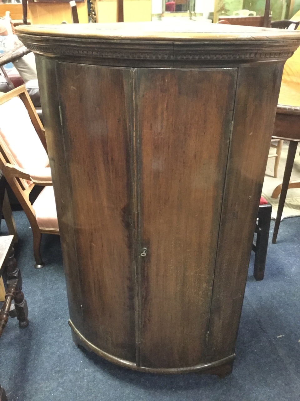 A barrel fronted nineteenth century mahogany corner cabinet with moulded dentil cornice above two