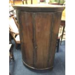 A barrel fronted nineteenth century mahogany corner cabinet with moulded dentil cornice above two