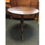 A circular Georgian country oak snap-top occasional table, supported on turned baluster column