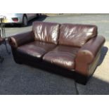 A leather two-seater sofa with loose cushions, the stitched panelled settee on block feet. (72in)