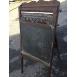 A childs blackboard easel in carved oak frame, the top panel with roller displaying various