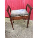An Edwardian piano stool with upholstered box seat flanked by splayed shaped handles, supported on