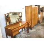 A 1960s walnut bedroom suite with three door wardrobe, bowfronted dressing table, a pair of