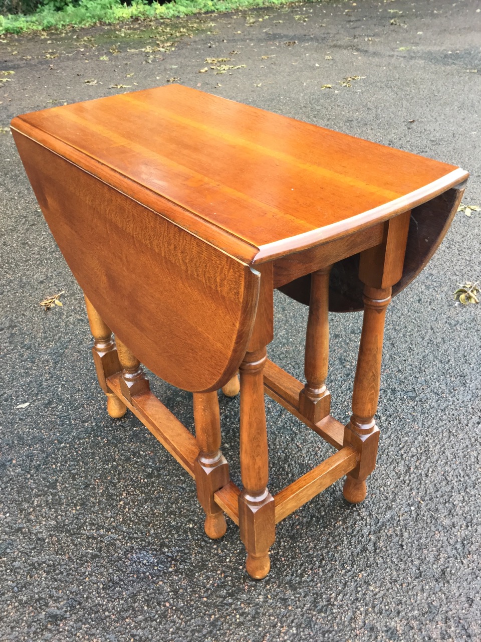 An oval oak gateleg dining table, the moulded top with two drop-leaves raised on baluster turned