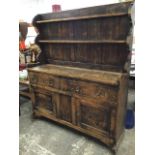 An oak dresser, the panelled delft rack with two plate shelves and shaped sides above a base with