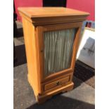 A glazed birch cabinet with moulded top above a bevelled glass door having drawer below, raised on