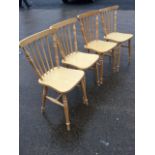 A set of four beech kitchen chairs with spindle backs above shaped seats, raised on turned legs &