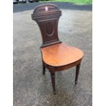 A nineteenth century mahogany hall chair, the waisted back with oval panel beneath a carved band and
