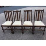 A set of four oak dining chairs, the arched slat backs with lozenge and bead decoration above drop-