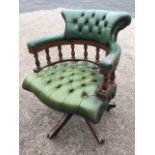 A leather button upholstered captains chair, the rounded back with brass studding supported on