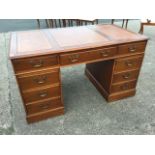 A reproduction mahogany kneehole desk, the rectangular moulded top set with gilt tooled leather