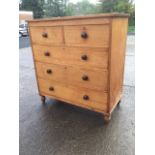 A Victorian pine chest of drawers with two short and three long drawers mounted with knobs, raised
