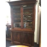 An early Victorian mahogany bookcase with angled cornice above glazed doors enclosing shelves