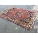 An antique oriental rug woven with central ink blue serrated floral medallion with ladder pendants