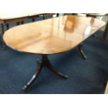 A Georgian style mahogany dining table, the crossbanded top with rounded ends and spare leaf