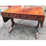 A regency rosewood sofa table, the brass strung top with two drop flaps above a frieze with twin