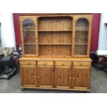 A Ducal pine kitchen dresser, the back with rounded cornice above open shelves flanked by arched