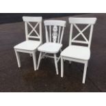 A pair of white painted chairs, the backs with crossed battens above shaped solid seats, raised on