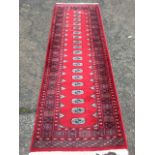 An oriental style runner woven with band of nineteen oval medallions in red field bordered by hooked