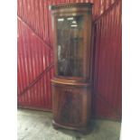 A reproduction mahogany corner cabinet with moulded dentil cornice above astragal glazed door, the