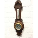 A Victorian carved oak barometer, the leaf carved scrolled frame mounted with thermometer above a