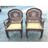 A pair of nineteenth century Chinese hardwood armchairs, the arched shaped backs with rounded frames