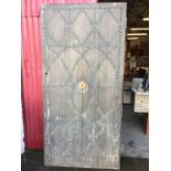 A large oak door with decorative hobnail studding having panelled back, mounted with four brass