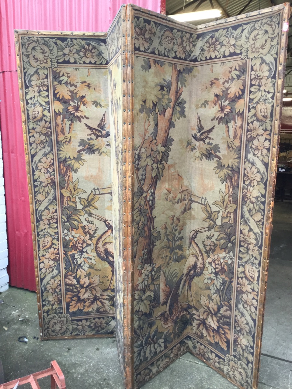 A tall four-fold antique tapestry screen, the woven panels depicting birds in landscapes framed by