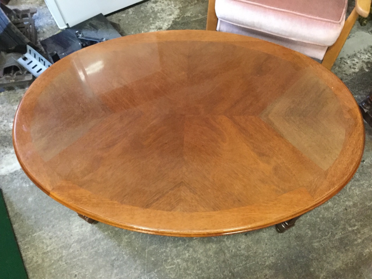 An oval reproduction mahogany coffee table, the quarter veneered crossbanded top above a moulded