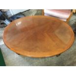 An oval reproduction mahogany coffee table, the quarter veneered crossbanded top above a moulded