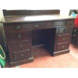 A Victorian mahogany kneehole desk, the rounded moulded top with shaped upstand having two frieze