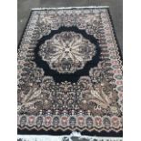 A floral carpet woven with circular paisley style medallion and border on black ground, within a