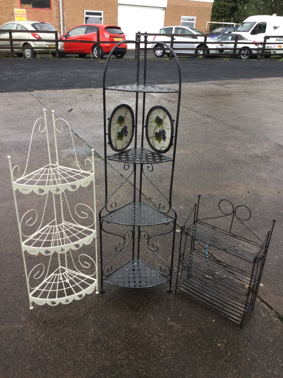 A modern folding corner stand with four graduated plaited rounded triangular shelves on scrolled