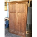 A late Victorian oak wardrobe with moulded ogee cornice above panelled doors enclosing an interior